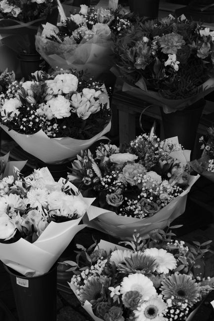 A variety of fresh flower bouquets displayed on a table, featuring an assortment of blooms such as roses, daisies, and chrysanthemums in different sizes and arrangements. The flowers are wrapped in ti