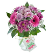 Capturing the colourful essence of Lower Clapton, this radiant bouquet features a bold mosaic of fuchsia pink Gerbera daisies, soft lavender roses, and deep magenta chrysanthemums, each carefully arranged in a clear, textured glass vase that sparkles in the light. The rounded arrangement is packed with plush petals-the hot pink Gerberas commanding attention with their dark centers, nestled beside gentle lilac roses whose softness contrasts perfectly with the vibrant palette. Sprigs of white baby's breath, woven between the larger blooms, lend a delicate, uplifting buoyancy, while rich, green leaves frame and support the bouquet with understated elegance. The vase is tied with rustic natural raffia, its relaxed bow holding a blank white tag for a personalised birthday, anniversary, or thank-you message. This bouquet, inspired by the diversity and warmth of Lower Clapton's community, is an ideal floral gift for commemorating life's joyful milestones or sharing a heartfelt sentiment, delivered straight to homes within E5 and the wider Hackney area.