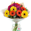 This joyful bouquet of Gerbera daisies captures the exuberance of Lower Clapton life, offering a radiant burst of colour and energy curated by passionate local florists. Presented in a slender glass vase, the arrangement showcases a balanced mix of sunny yellow, bold orange, and vivid fuchsia blooms, each punctuated by a contrasting deep centre that adds stunning dimension. Glossy green leaves peek between the blossoms, their freshness reminiscent of walks through Hackney Marshes. The bouquet is wrapped in rustic kraft paper and protected by cellophane, its layers securing the delicately hand-tied stems visible through the glass. Holding everything together is a strand of textured brown twine, finished with a charming white tag featuring a red rose emblem-hinting at personal sentiment or a celebratory message. The bouquet's composition and flawless condition make it ideal for special occasions, cheerful home décor, or thoughtful deliveries throughout Lower Clapton's lively community-from the corner cafes to the tranquil edges of Millfields Park. Each flower radiates warmth, joy, and the authentic touch of a neighbourhood expert, making this bouquet a beacon of happiness and artistry.